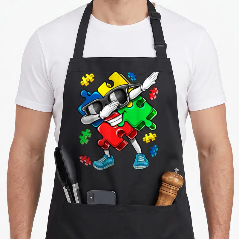 Tablier de cuisine noir avec un puzzle anthropomorphique en dab portant des lunettes noires et des chaussures bleues.