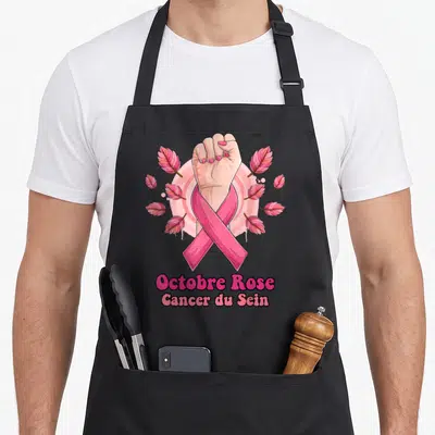 Tablier de cuisine noir avec ruban rose, poing levé et inscription Octobre Rose Cancer du Sein.