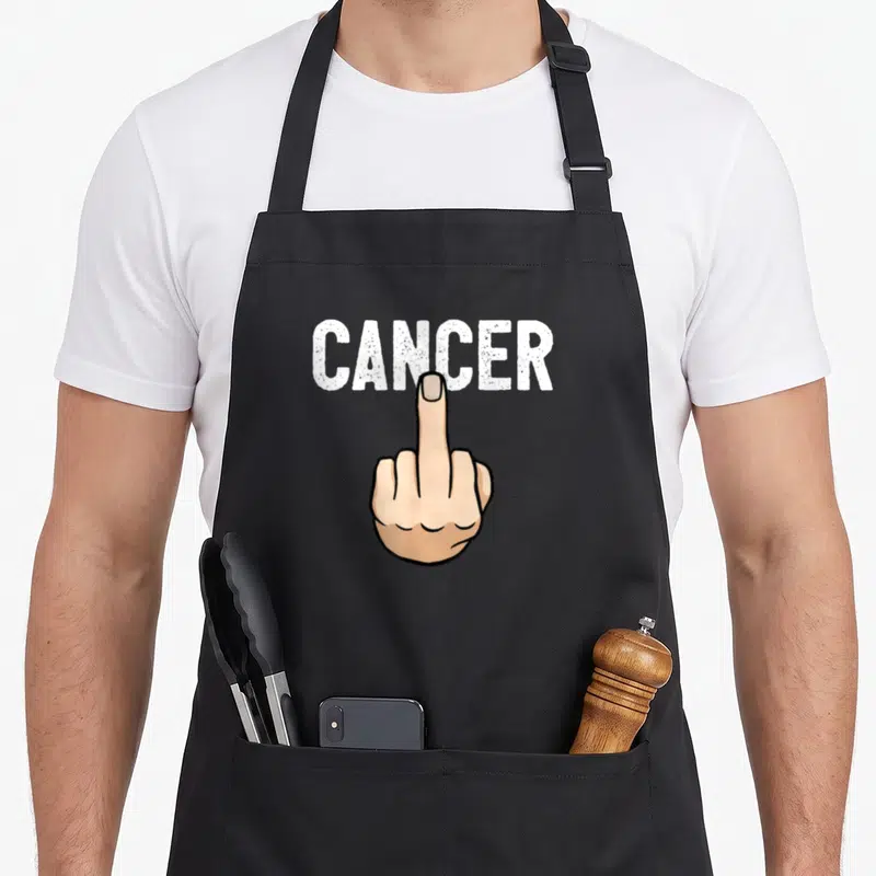 Tablier de cuisine noir avec l'inscription CANCER et une main faisant un signe d'offense en dessous.