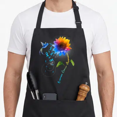 Tablier de cuisine noir avec colibri bleu, tournesol coloré et rubans de sensibilisation au cancer de l'ovaire.