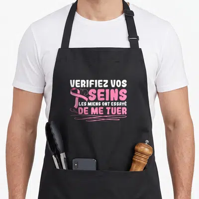 Tablier de cuisine noir avec inscription Vérifiez vos Seins et ruban rose stylisé.