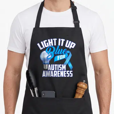 Tablier de cuisine noir avec une ampoule bleue, un ruban et le texte Light It Up Blue for Autism Awareness.