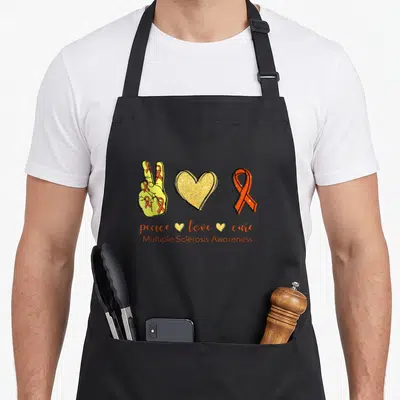 Tablier de cuisine noir avec main peace, cœur doré pailleté et ruban orange pour la sensibilisation à la sclérose en plaques.