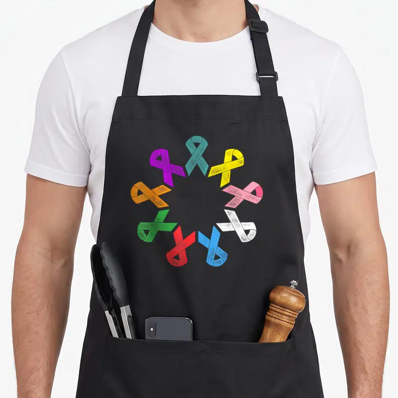 Tablier de cuisine noir avec un cercle de rubans multicolores à texture esquissée représentant divers cancers.