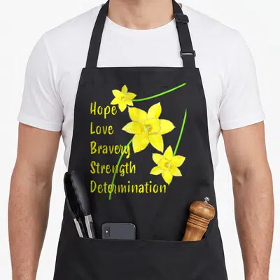 Tablier de cuisine noir avec trois jonquilles jaunes et les mots Hope Love Bravery Strength Determination imprimés en jaune.