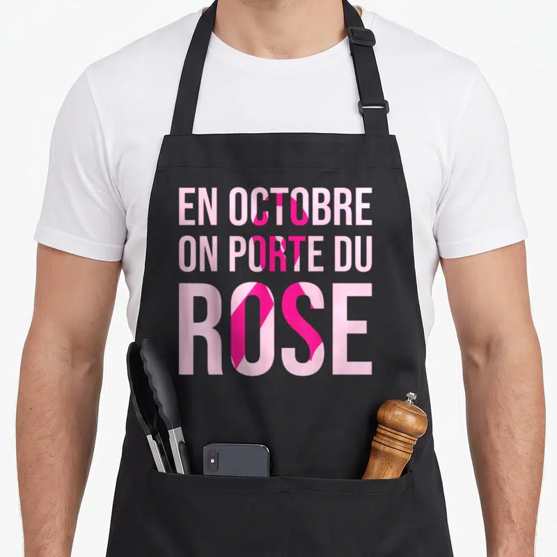 Tablier de cuisine noir avec l'inscription En Octobre On Porte Du Rose en rose et ruban stylisé,