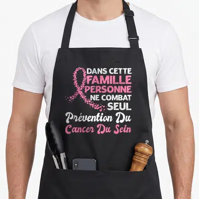 Tablier de cuisine noir avec un ruban rose fait de cœurs et du texte blanc et rose sur fond uni.