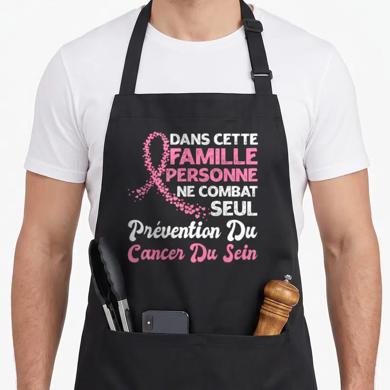 Tablier de cuisine noir avec un ruban rose fait de cœurs et du texte blanc et rose sur fond uni.