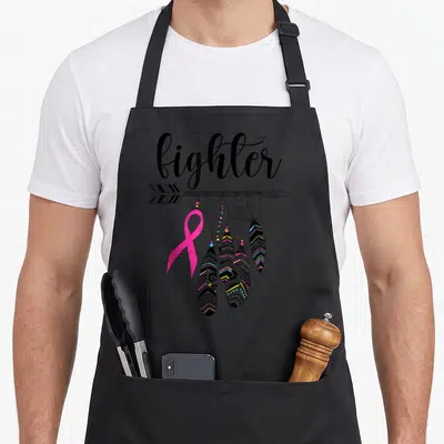 Tablier de cuisine noir avec inscription fighter, ruban rose et plumes décoratives sur une flèche.