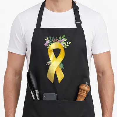 Tablier de cuisine noir avec un ruban doré aquarellé et une couronne de fleurs violettes et de feuilles vertes.