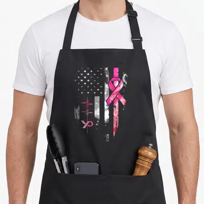 Tablier de cuisine noir avec un grand ruban rose et une ligne de vie stylisée sur fond texturé.