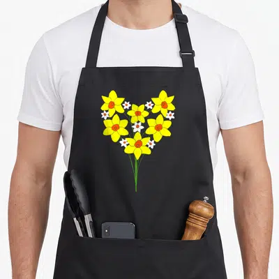 Tablier de cuisine noir avec bouquet de jonquilles jaunes et blanches formant un cœur sur fond uni.