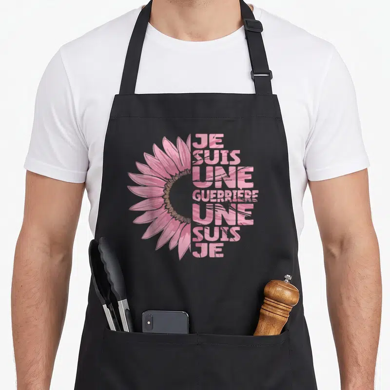 Tablier de cuisine noir orné d'une grande tournesol rose et du texte vertical Je Suis Une Guerrière.