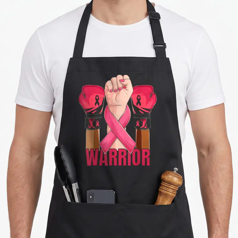 Tablier de cuisine noir avec illustration de gants de boxe roses, poing levé et texte Warrior en bas.