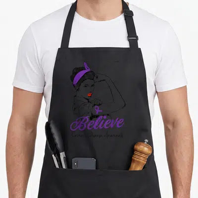 Tablier de cuisine noir avec une femme au ruban violet et le mot Believe imprimé en violet.