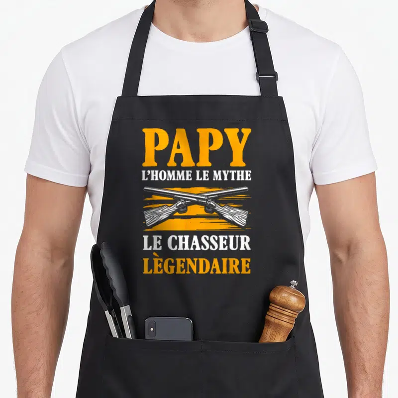 Tablier de cuisine noir avec fusils croisés et texte Papy l'homme le mythe chasseur légendaire en orange et blanc.