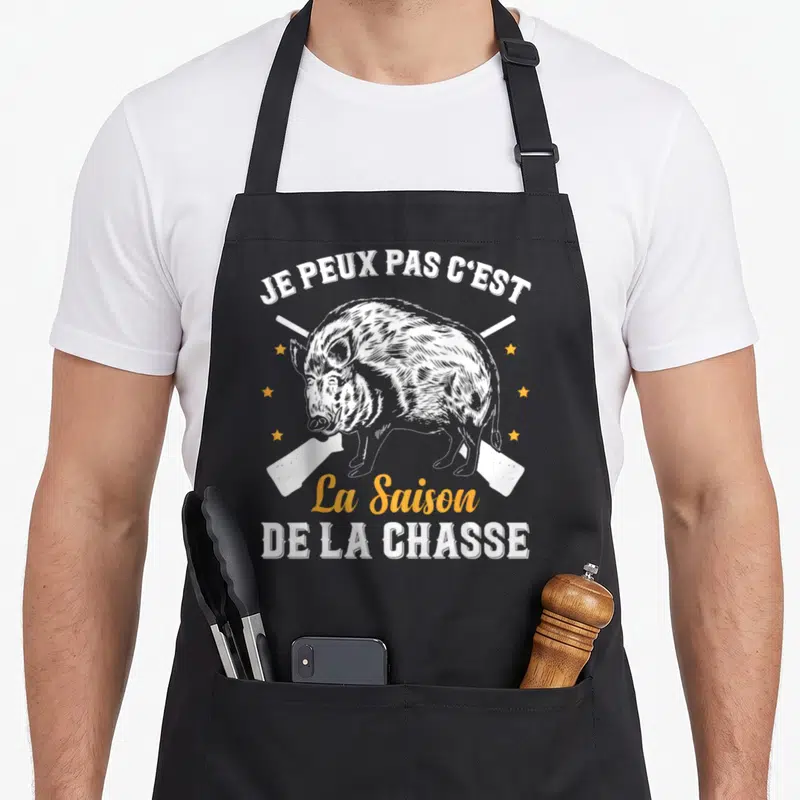 Tablier de cuisine noir avec illustration de sanglier et fusils croisés en blanc et orange.