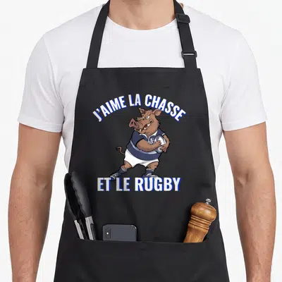 Tablier de cuisine noir avec un sanglier en maillot de rugby tenant un ballon et les mots J'aime la chasse et le rugby.