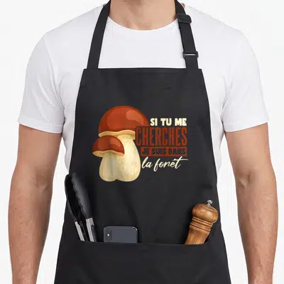 Tablier de cuisine noir avec illustration de deux cèpes et le texte Si tu me cherches je suis dans la forêt.