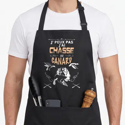 Tablier de cuisine noir avec inscription J'ai chasse au canard et illustration d'un chien de chasse blanc.