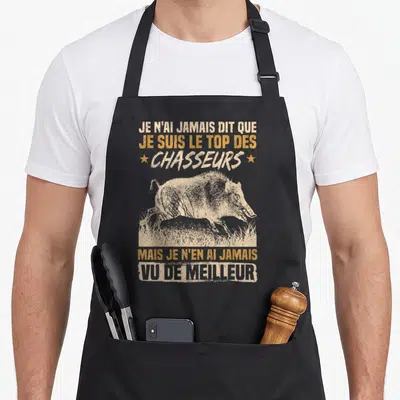 Tablier de cuisine noir avec une illustration de sanglier et le texte Je suis le top des chasseurs en lettres orange et blanches.