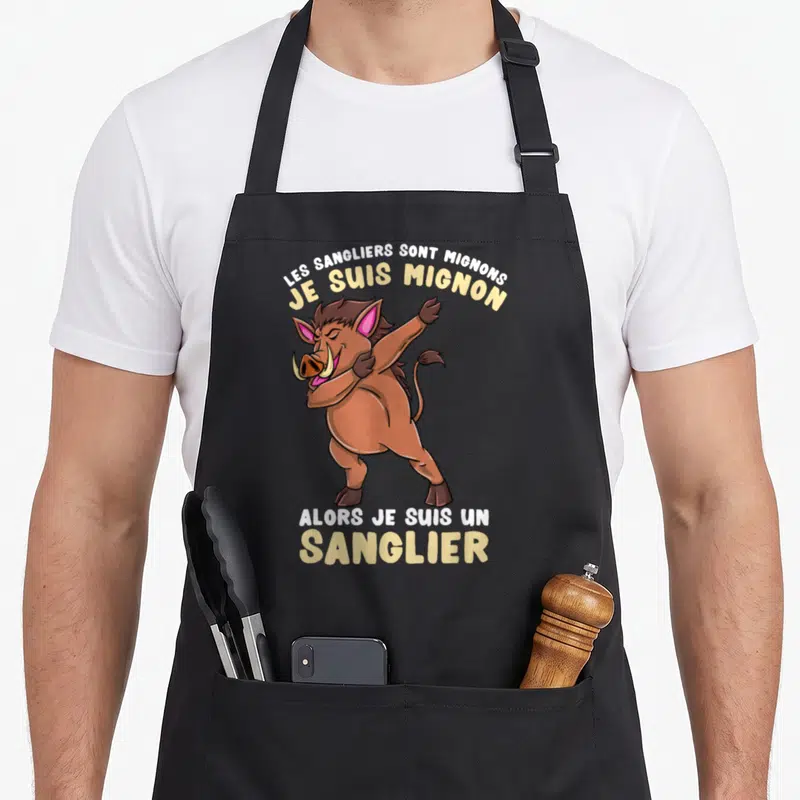 Tablier de cuisine noir avec un sanglier marron effectuant une pose dab et du texte humoristique jaune et blanc.