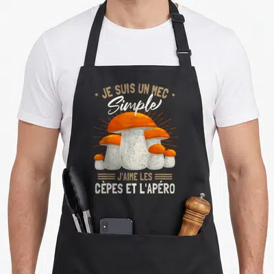 Tablier de cuisine noir avec illustration de cèpes orange et texte blanc soulignant l'amour des champignons et des boissons.