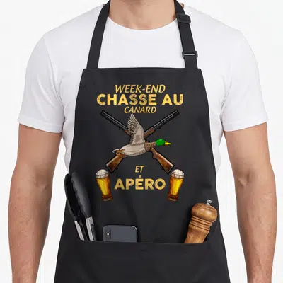 Tablier de cuisine noir avec illustration d'un canard volant sur deux fusils croisés et deux verres de bière en bas.