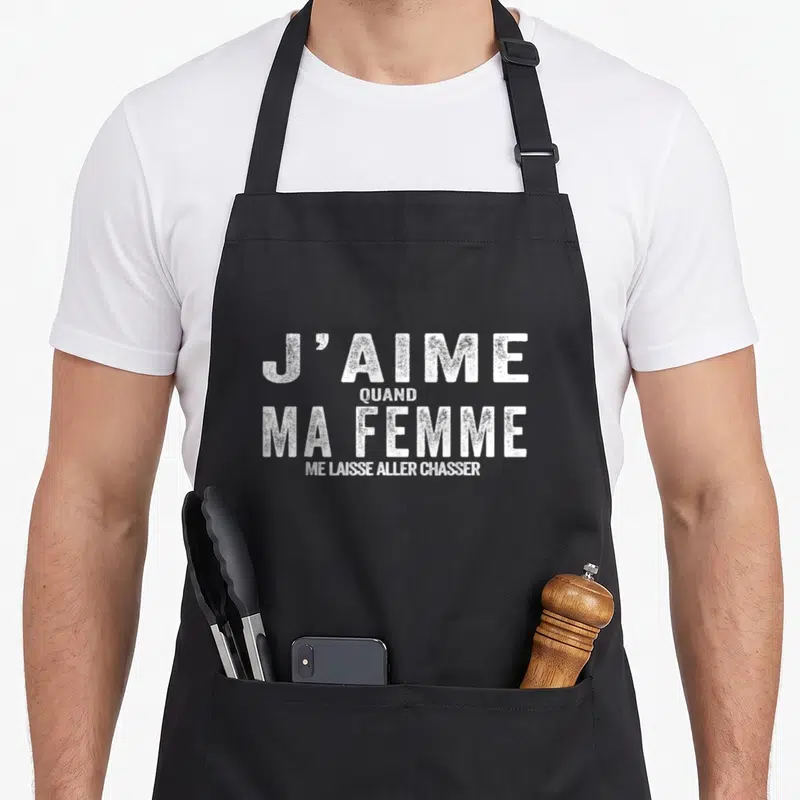 Tablier de cuisine noir avec inscription blanche J'aime quand ma femme me laisse aller chasser en typographie texturée.