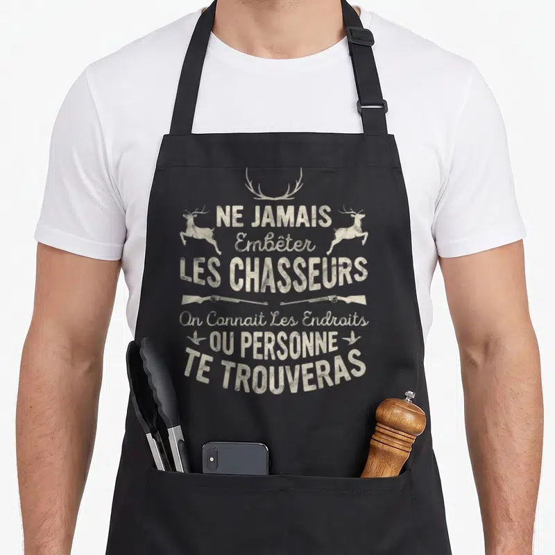 Tablier de cuisine noir avec texte beige Ne jamais embêter les chasseurs et illustrations de cerfs et fusils.
