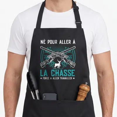 Tablier de cuisine noir avec deux fusils croisés, un cerf et le texte Né pour aller à la chasse.