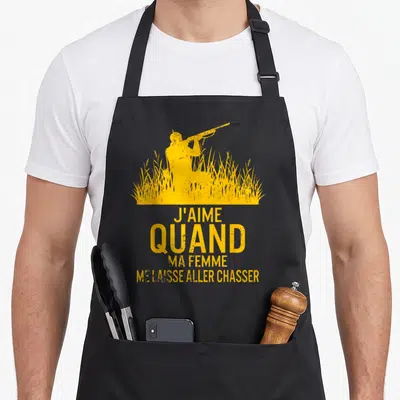 Tablier de cuisine noir avec silhouette jaune d'un chasseur dans les hautes herbes et texte humoristique imprimé au centre.