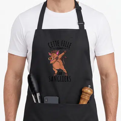Tablier de cuisine noir avec illustration d'un sanglier effectuant une pose dab et le texte Cette Fille aime les sangliers.