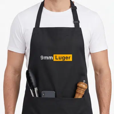 Tablier de cuisine noir avec inscription 9mm Luger en blanc et gris sur un rectangle orange vif au centre.