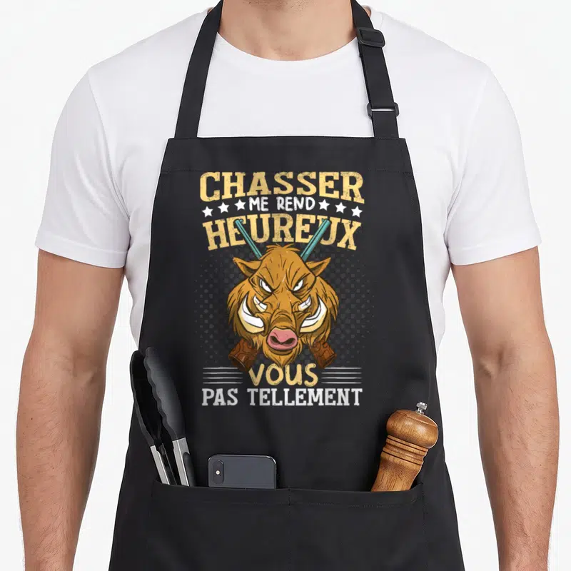 Tablier de cuisine noir avec tête de sanglier, fusils croisés et texte humoristique en jaune et blanc.