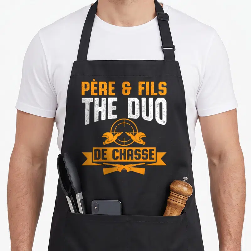 Tablier de cuisine noir avec inscription Père & Fils The Duo de Chasse et deux carabines croisées orange.