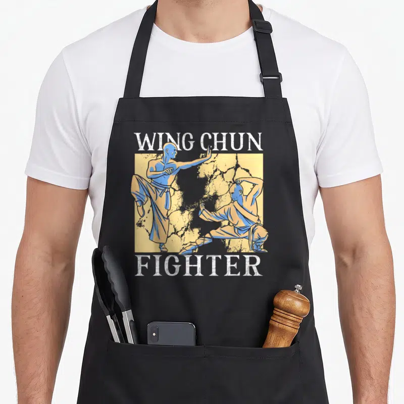 Tablier de cuisine noir avec illustration de deux pratiquants de Wing Chun et le texte WING CHUN FIGHTER en blanc.