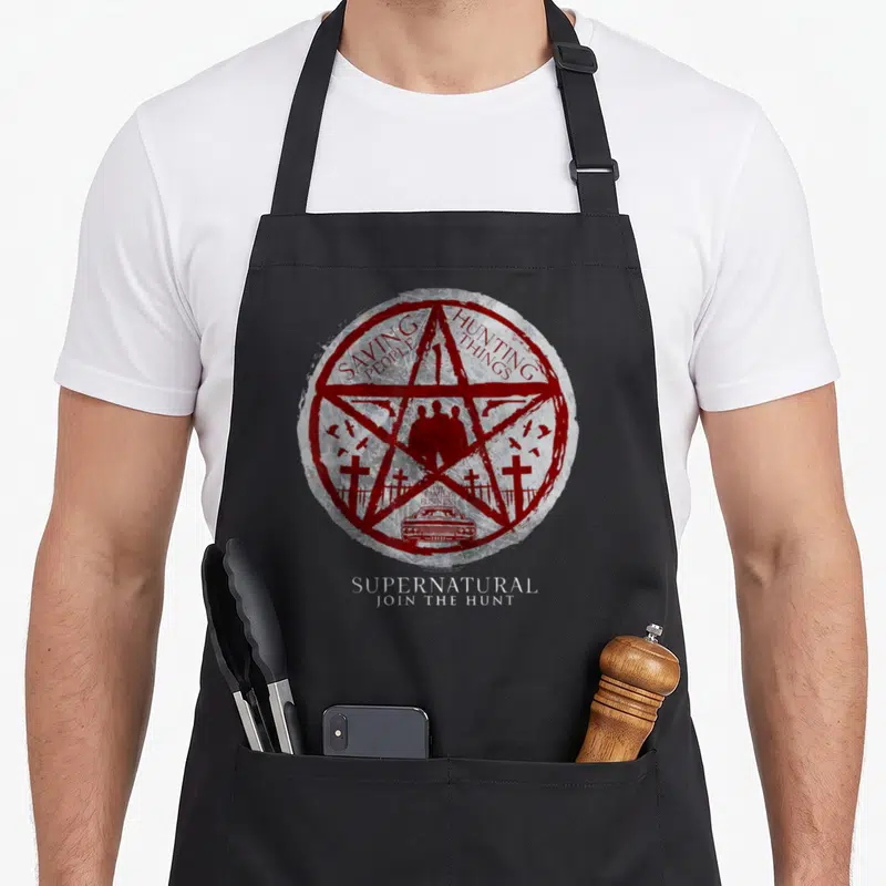 Tablier de cuisine noir avec un pentagramme rouge, des silhouettes et le texte « Saving People Hunting Things » imprimé en cercle.