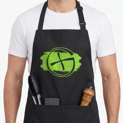 Tablier de cuisine noir avec logo circulaire vert lime représentant une croix et des lignes de géocaching stylisées.