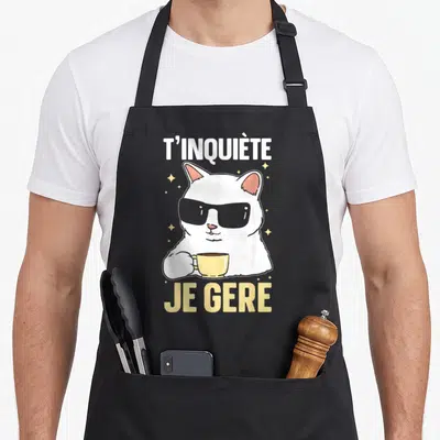 Tablier de cuisine noir avec un chat blanc portant des lunettes noires et tenant une tasse jaune.