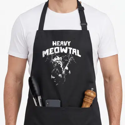 Tablier de cuisine noir avec illustration blanche d'un chat jouant de la guitare électrique sous le texte Heavy Meowtal et des éclairs.