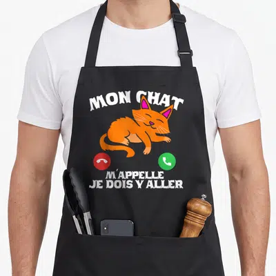 Tablier de cuisine noir avec un chaton orange dormant et des icônes téléphoniques rouge et verte sous le texte blanc.