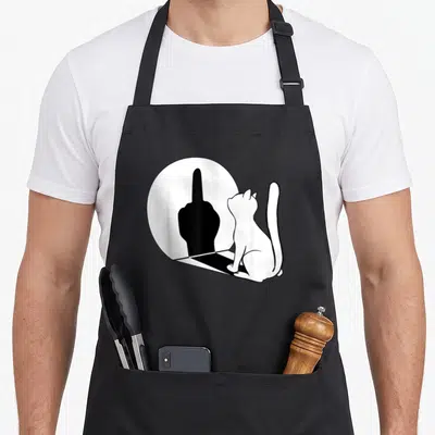 Tablier de cuisine noir avec illustration d'un chat regardant son reflet en forme de doigt d'honneur dans un miroir circulaire.