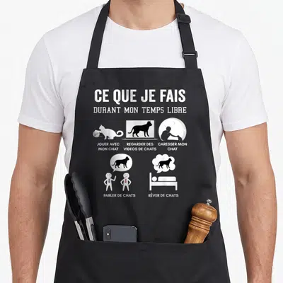 Tablier de cuisine noir avec inscription Ce que je fais durant mon temps libre et illustrations de chats en blanc.
