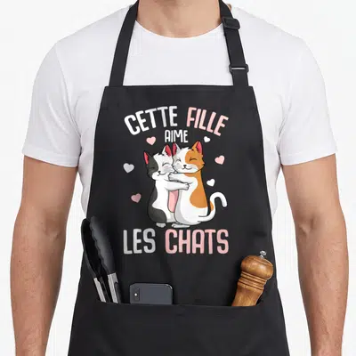 Tablier de cuisine noir avec deux chats s'embrassant et le texte Cette Fille Aime Les Chats en blanc et rose.