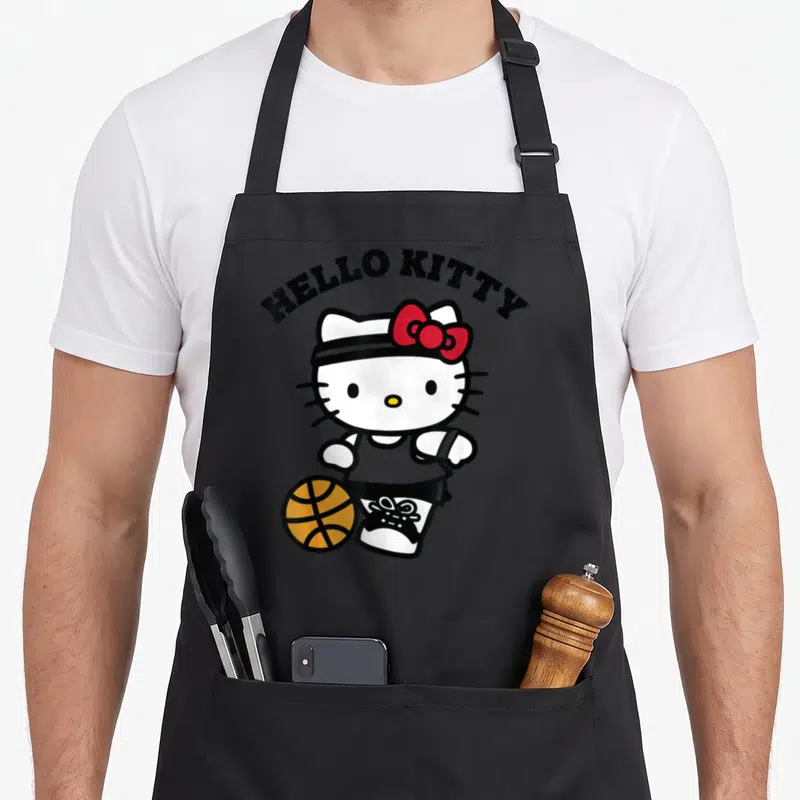 Tablier de cuisine noir avec Hello Kitty en tenue de basket dribblant un ballon orange.