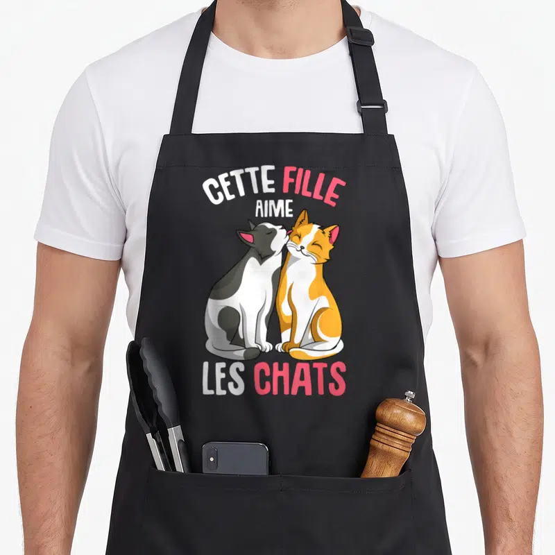 Tablier de cuisine noir avec deux chats s'embrassant et le texte Cette Fille Aime Les Chats en blanc et rose.
