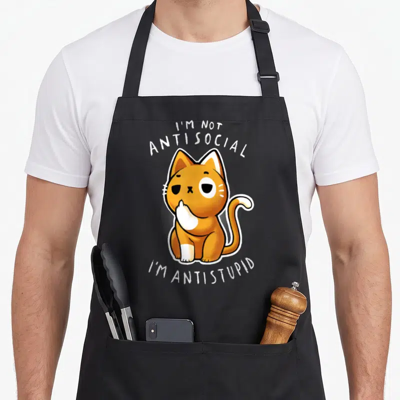 Tablier de cuisine noir avec illustration d'un chat orange et blanc posant une patte sur sa bouche avec texte blanc.