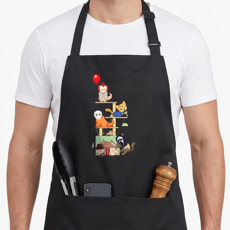 Tablier de cuisine noir avec des chats déguisés en personnages de films d'horreur sur un meuble à chat.