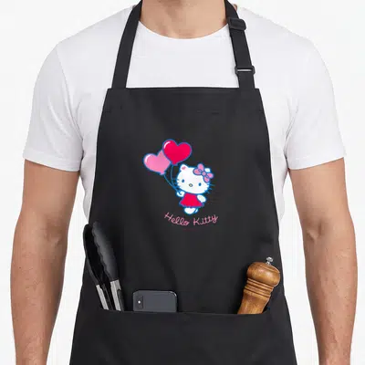 Tablier de cuisine noir avec Hello Kitty tenant des ballons en forme de cœur roses et rouges, signature rose en dessous.